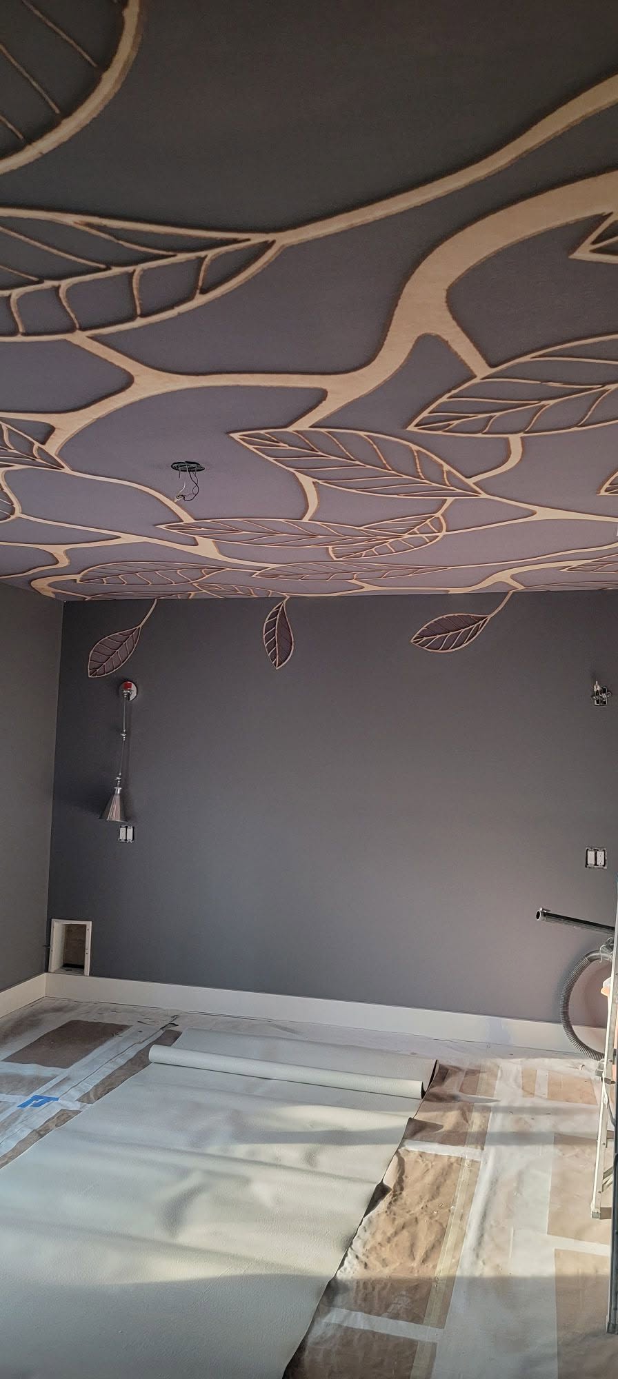 Leaf-pattern specialty wallcovering installed across a ceiling and wall